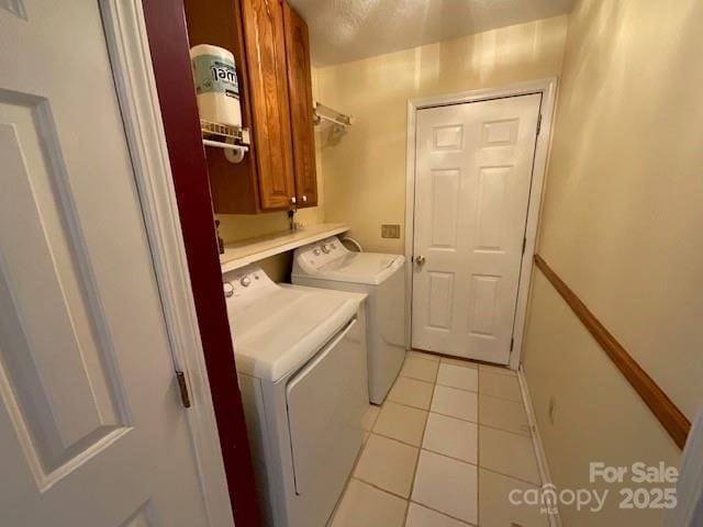 laundry area featuring light tile patterned flooring, cabinets, and washing machine and dryer