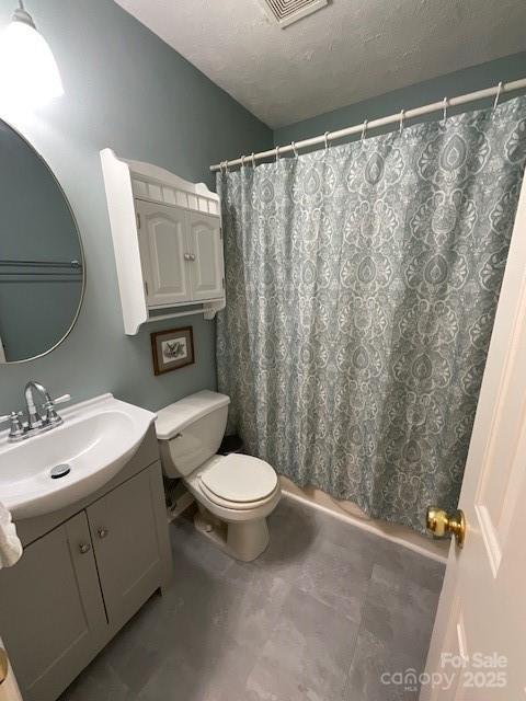 bathroom featuring vanity, a textured ceiling, and toilet