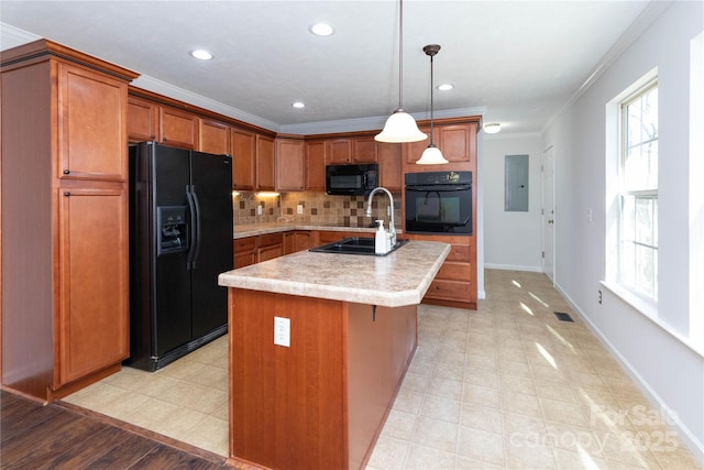 kitchen featuring pendant lighting, a kitchen island with sink, plenty of natural light, ornamental molding, and black appliances