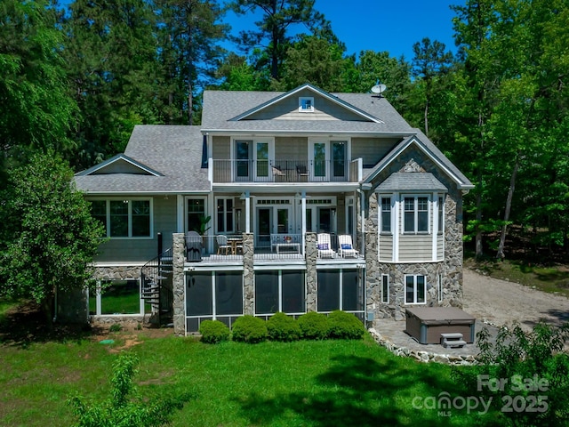 rear view of house featuring a balcony, french doors, a hot tub, and a yard