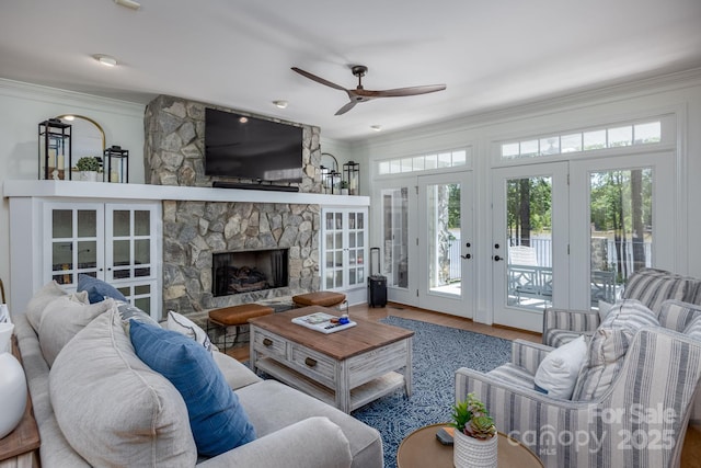 living room featuring french doors, a fireplace, hardwood / wood-style flooring, ceiling fan, and crown molding