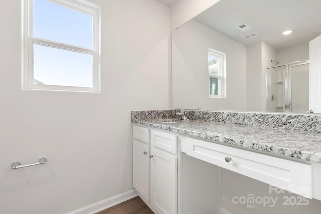 bathroom with a shower with shower door and vanity