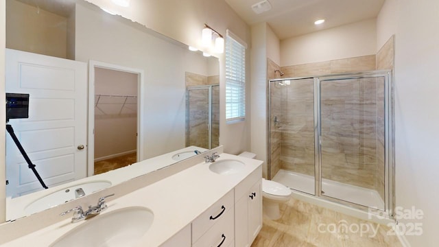 bathroom featuring toilet, a shower with shower door, and vanity