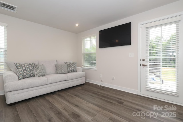 living room with a wealth of natural light and dark hardwood / wood-style flooring