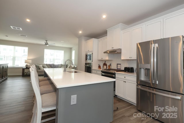 kitchen with a center island with sink, a breakfast bar, sink, appliances with stainless steel finishes, and white cabinets