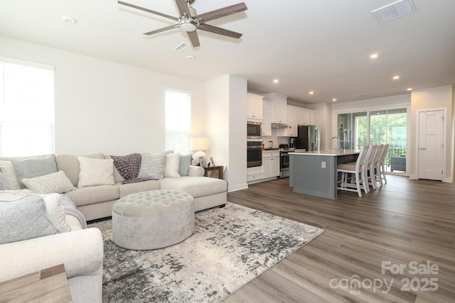 living room with ceiling fan and dark hardwood / wood-style flooring