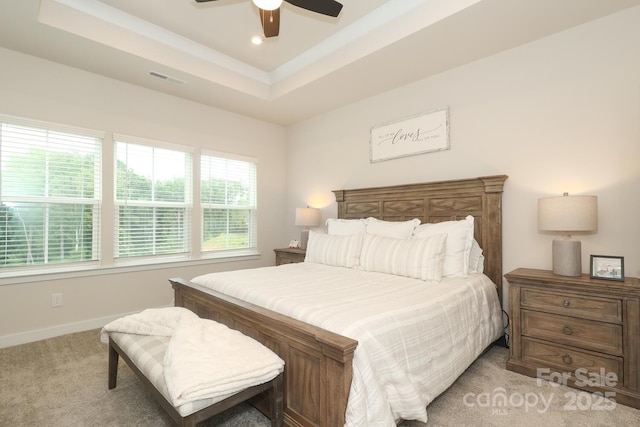 bedroom with ceiling fan, light colored carpet, and a raised ceiling