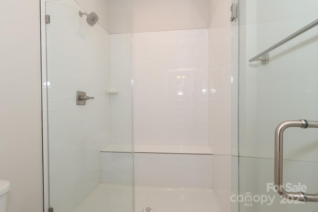 bathroom with a shower with shower door and toilet