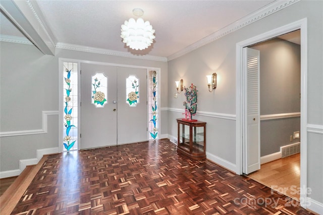 foyer featuring crown molding, a notable chandelier, and dark parquet flooring