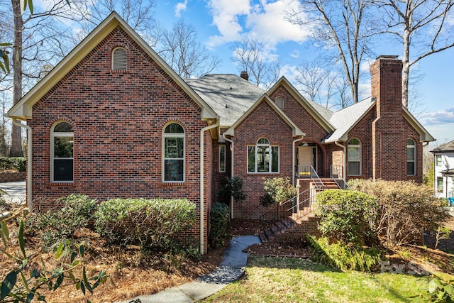 view of front of property featuring brick siding, roof with shingles, and a chimney