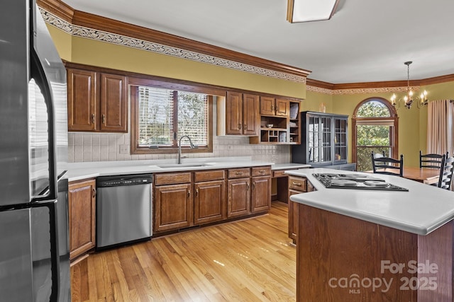 kitchen featuring open shelves, light wood-style flooring, a sink, stainless steel appliances, and light countertops