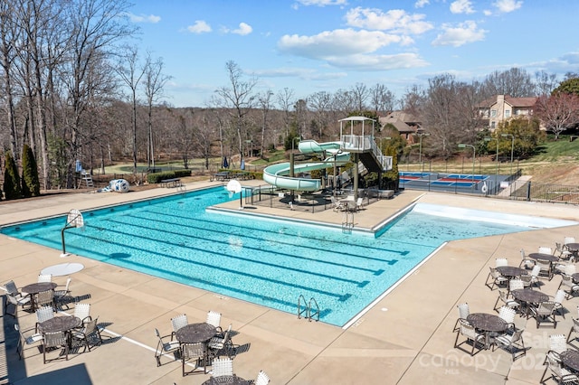 pool with a patio, fence, and a water slide