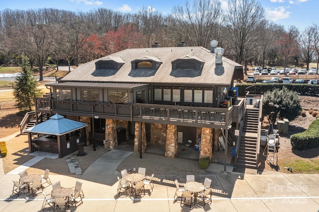 back of property with a patio area, stone siding, stairs, and a deck