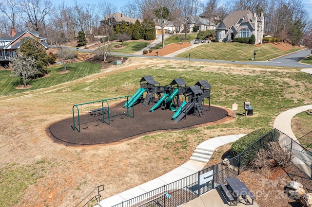 community jungle gym featuring a residential view, a lawn, and fence