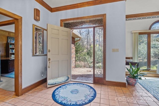 foyer featuring baseboards, light tile patterned flooring, and crown molding