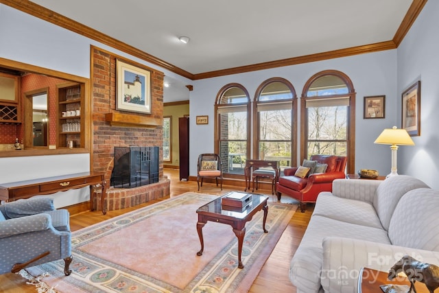 living room with ornamental molding, a brick fireplace, baseboards, and wood finished floors