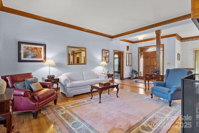 living area with decorative columns, wood finished floors, and ornamental molding