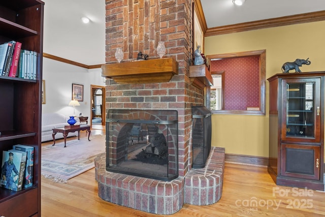 living area featuring baseboards, wood finished floors, ornamental molding, and a fireplace