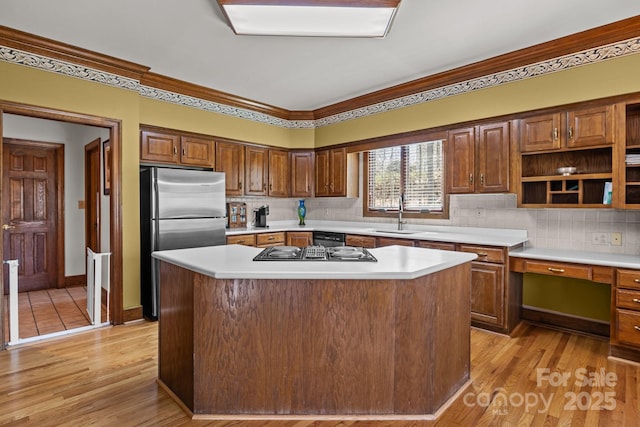 kitchen with a sink, light wood-type flooring, light countertops, and freestanding refrigerator