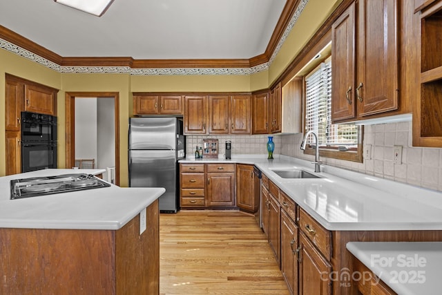 kitchen with a sink, light wood-type flooring, brown cabinets, and appliances with stainless steel finishes