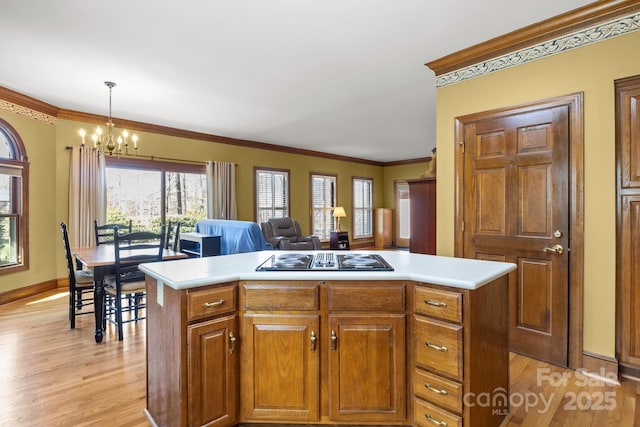 kitchen featuring light wood finished floors, stovetop with downdraft, crown molding, and light countertops