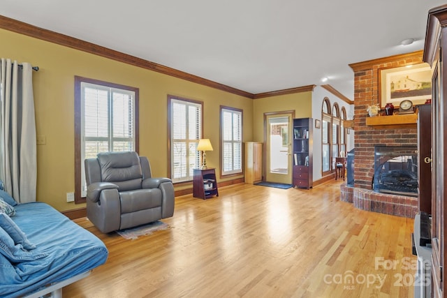 living room featuring baseboards, light wood-style floors, a brick fireplace, and ornamental molding