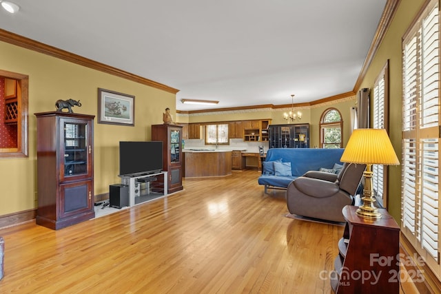 living area featuring baseboards, a chandelier, crown molding, and light wood finished floors