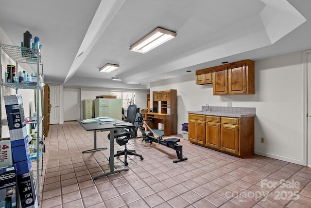 workout room featuring baseboards and light tile patterned flooring