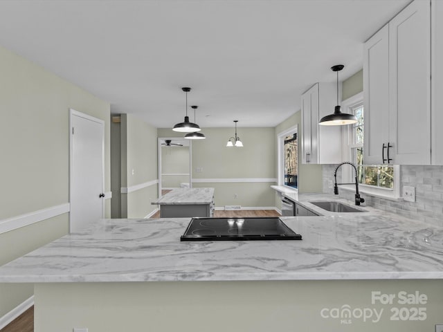 kitchen with black electric cooktop, light stone countertops, white cabinets, and sink