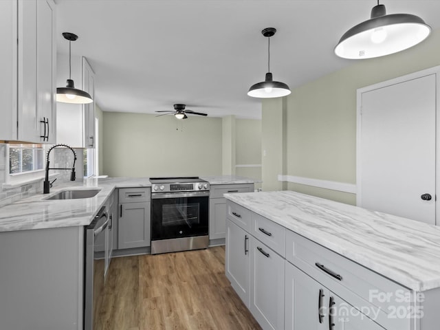 kitchen with appliances with stainless steel finishes, sink, gray cabinetry, and pendant lighting