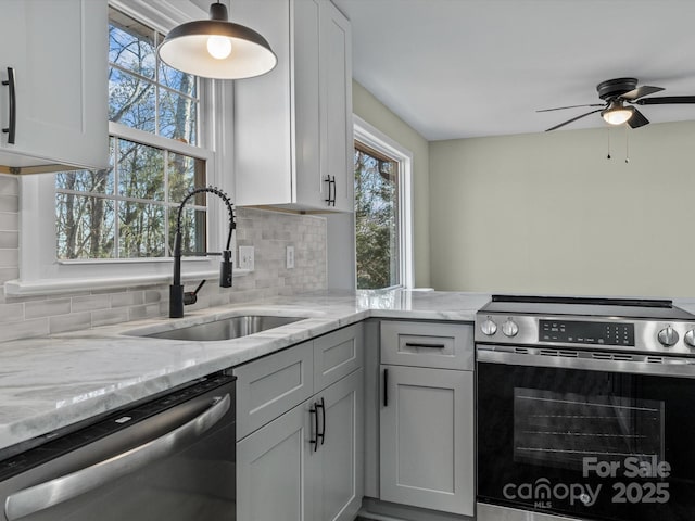 kitchen with tasteful backsplash, sink, white cabinetry, appliances with stainless steel finishes, and light stone counters