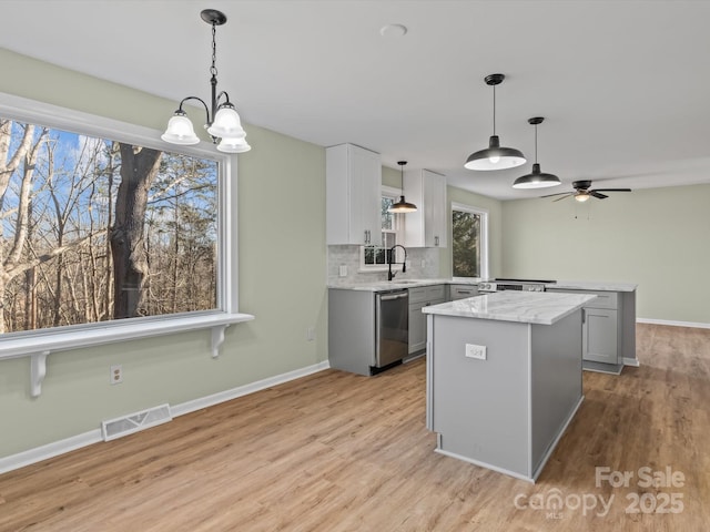 kitchen featuring a center island, sink, gray cabinetry, and pendant lighting