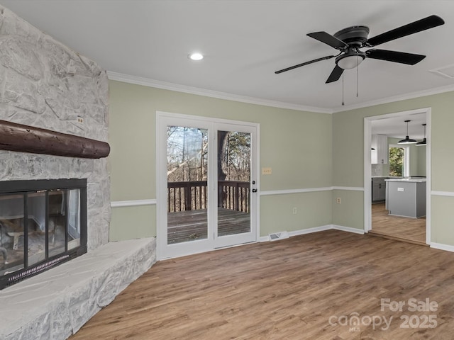 unfurnished living room with a fireplace, a wealth of natural light, ornamental molding, and hardwood / wood-style flooring