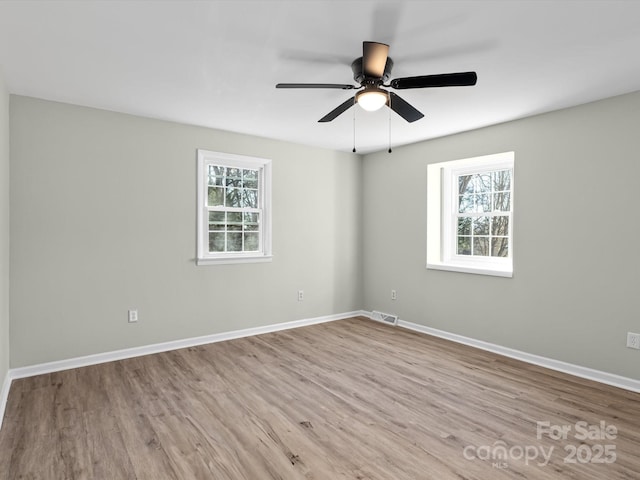 spare room with light hardwood / wood-style floors, a wealth of natural light, and ceiling fan