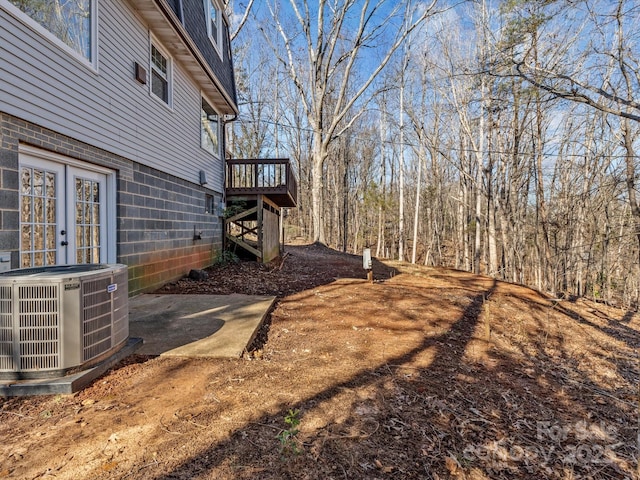 view of yard with a deck, french doors, and central air condition unit