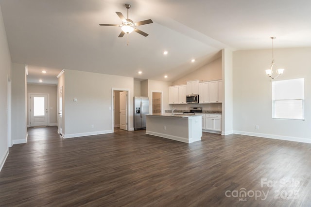 interior space with ceiling fan with notable chandelier, pendant lighting, white cabinetry, stainless steel appliances, and a kitchen island with sink