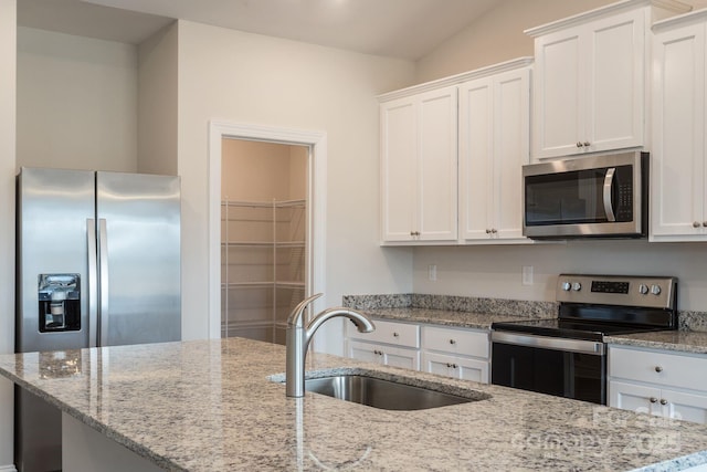 kitchen with lofted ceiling, white cabinetry, stainless steel appliances, sink, and light stone counters