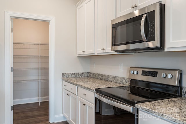 kitchen featuring light stone counters, dark wood-type flooring, white cabinetry, and stainless steel appliances