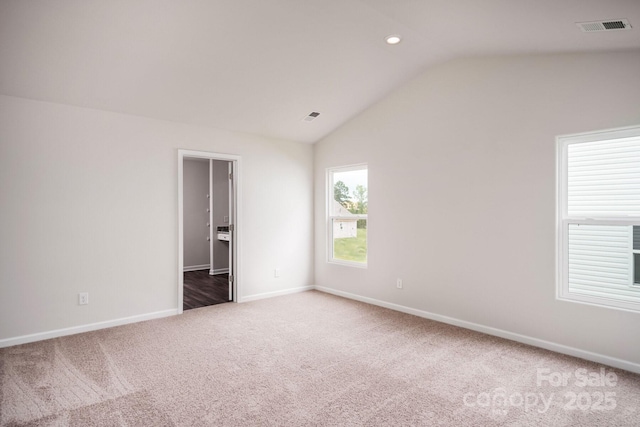 spare room featuring vaulted ceiling and carpet floors