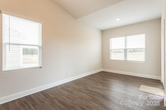 spare room with dark wood-type flooring and lofted ceiling