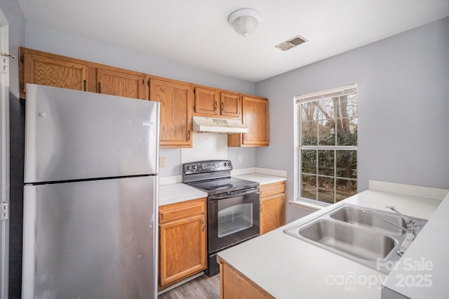 kitchen with stainless steel refrigerator, black / electric stove, sink, and light hardwood / wood-style flooring