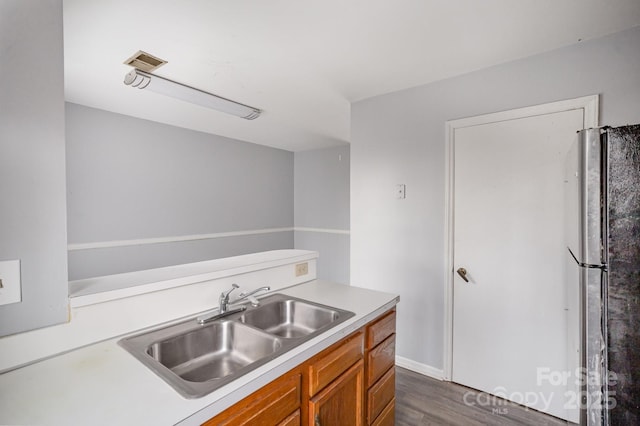 kitchen featuring dark hardwood / wood-style floors, stainless steel fridge, and sink