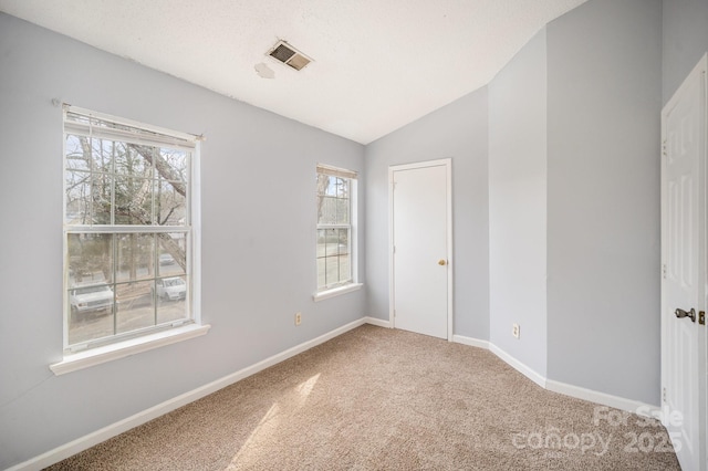 carpeted spare room featuring vaulted ceiling