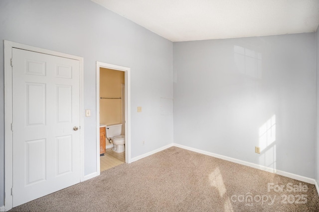 unfurnished bedroom featuring a closet, ensuite bath, and carpet