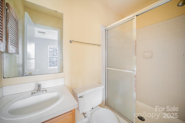 bathroom featuring an enclosed shower, vanity, and toilet