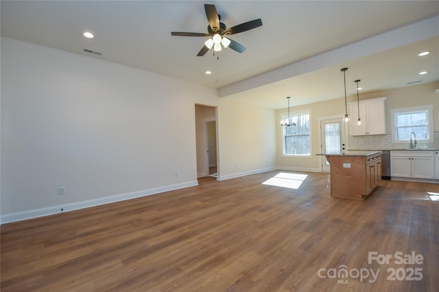 kitchen featuring tasteful backsplash, a kitchen island, stainless steel dishwasher, white cabinetry, and hanging light fixtures