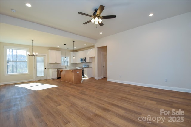 kitchen with pendant lighting, a center island, wood-type flooring, stainless steel appliances, and white cabinets