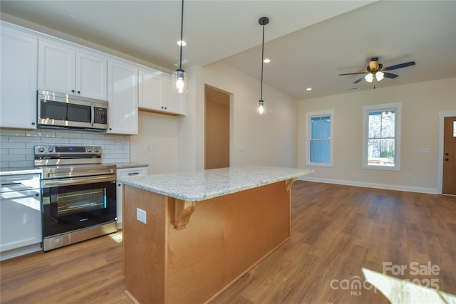 kitchen with pendant lighting, a center island, decorative backsplash, white cabinetry, and appliances with stainless steel finishes