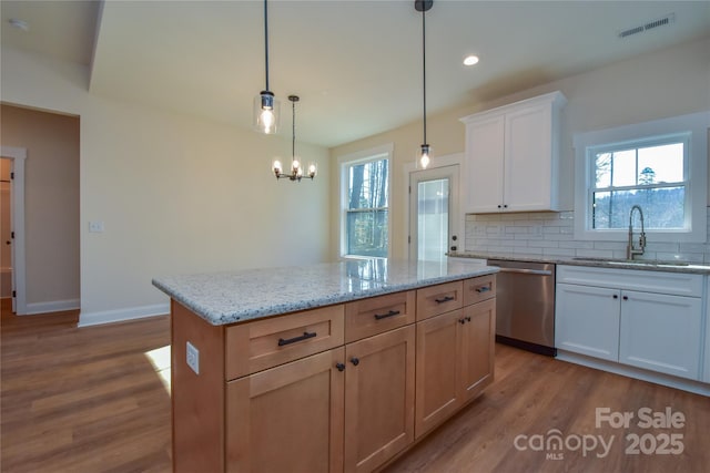 kitchen with white cabinetry, hanging light fixtures, a kitchen island, stainless steel dishwasher, and sink