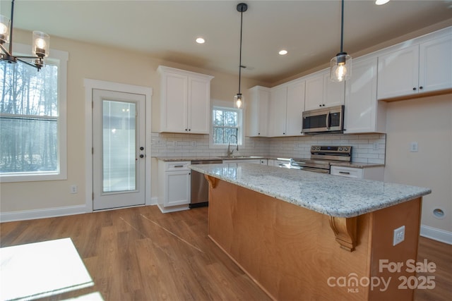 kitchen featuring hanging light fixtures, white cabinets, and stainless steel appliances